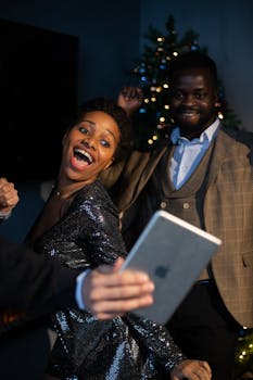 快乐的成年人在节日派对上通过视频通话拥抱技术，欢庆佳节