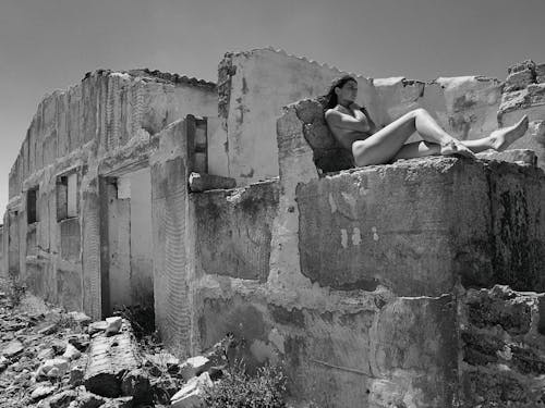 Grayscale Photo of Woman Sitting on Concrete Wall