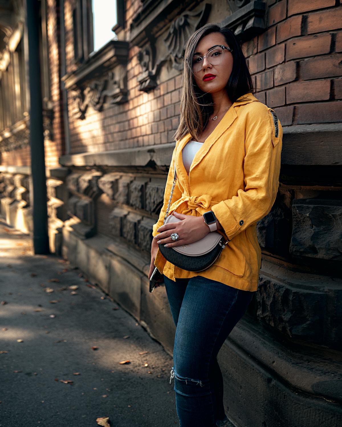 Ritratto street-style di donna con giacca senape e jeans denim