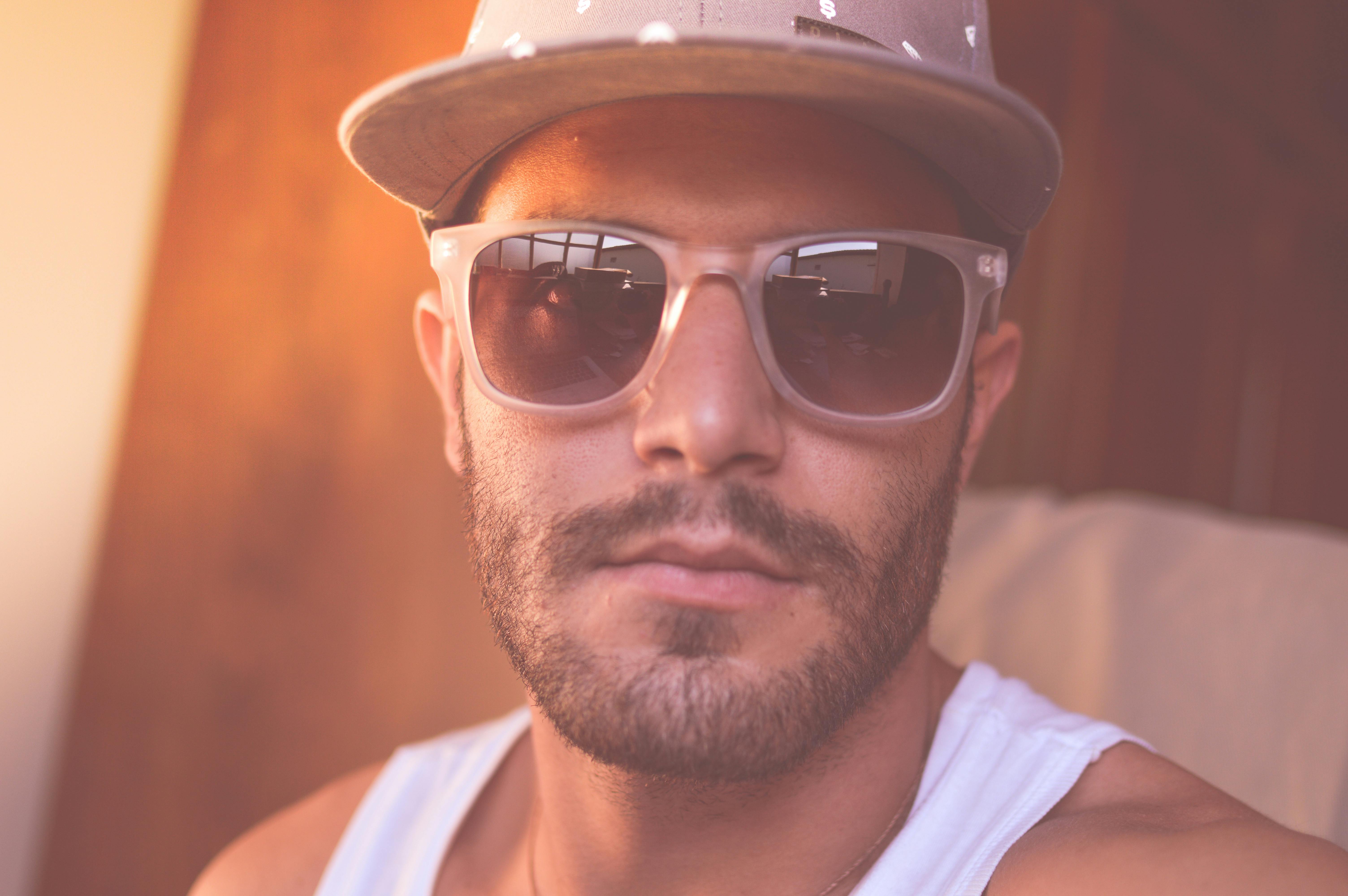 Foto Un hombre con gafas de sol y una camiseta blanca sin mangas –  Masculino Imagen en Unsplash