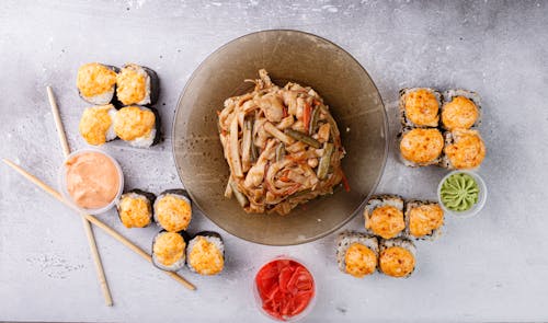 Appetizing Asian noodle and sushi rolls arranged on gray table