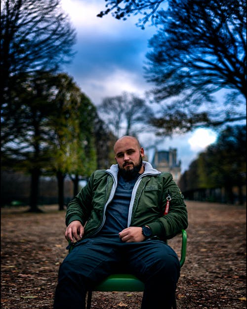 Photo of a Man Sitting on a Green Chair while Looking at the Camera
