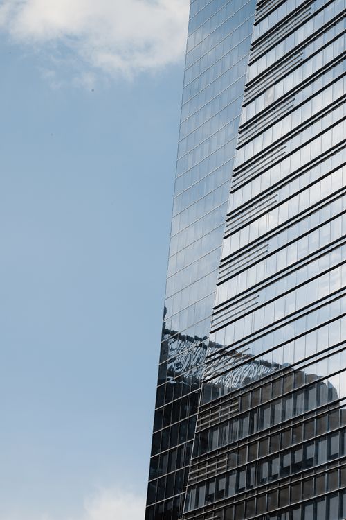 Free A skyscraper with reflective glass windows against a blue sky, showcasing urban architecture. Stock Photo