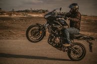 一名戴头盔的男子在开阔的道路上骑摩托车，展现了冒险与技巧