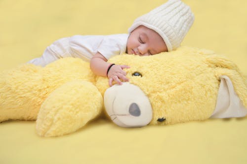Close-Up Photo of a Baby Sleeping on Top of a Yellow Stuffed Toy
