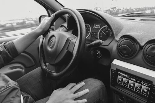 Crop man driving car on road