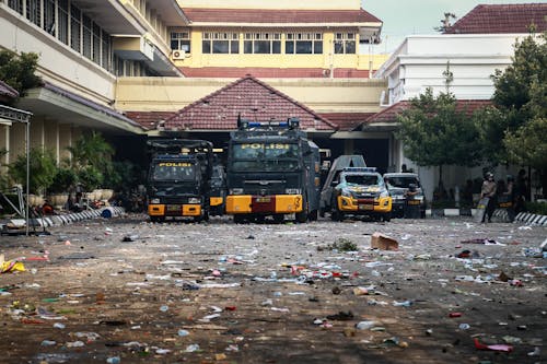 Police Vehicles Parked in Front of a Building with Trash on Pavement
