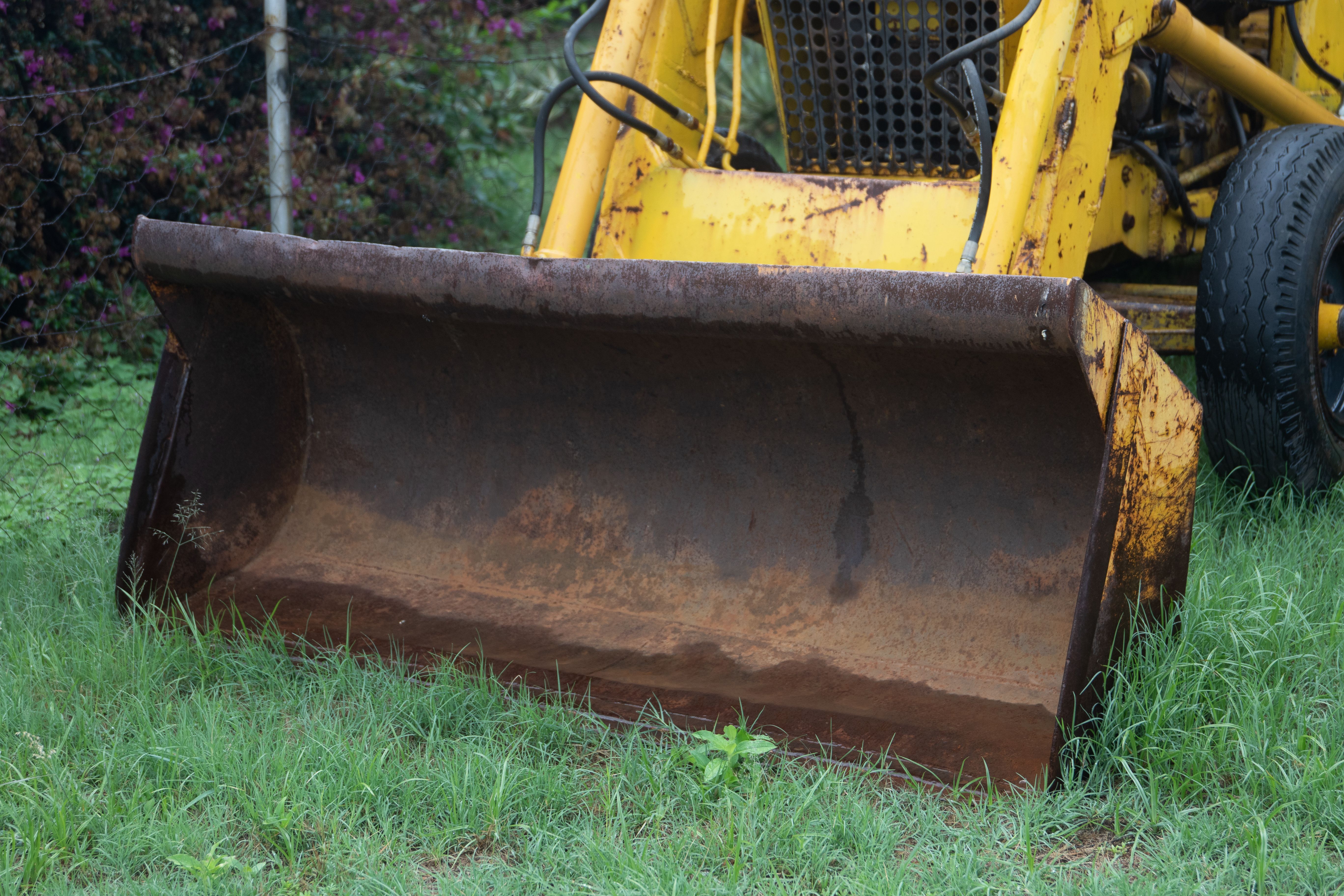 A worn Case 580 backhoe with hydraulic leaks sitting behind a contractor shop in central Arkansas