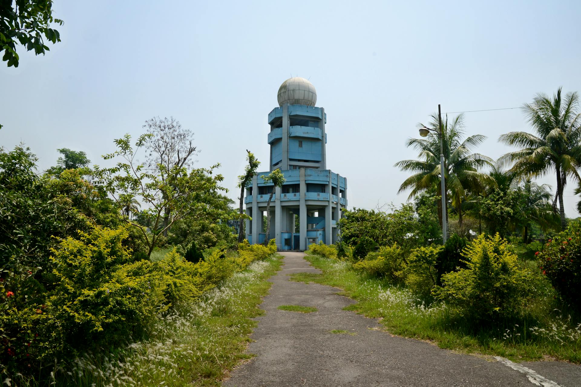 A radar tower set amidst green trees and bushes on a clear day.