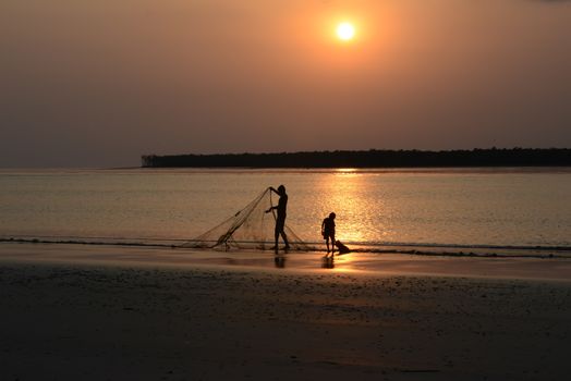 A fisherman and child casting nets at sunset, capturing the serene beauty of the ocean.