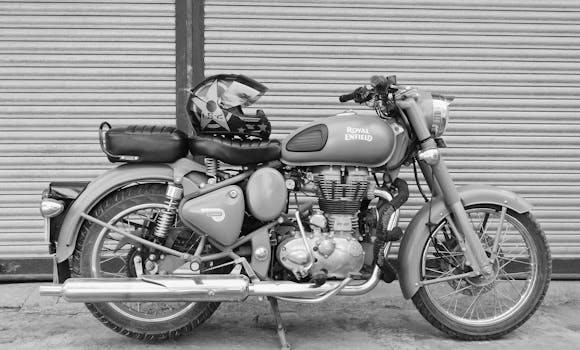 Vintage Royal Enfield motorcycle parked with helmet in grayscale, capturing its classic design.