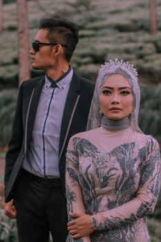 Stylish couple in formal traditional attire posing in an outdoor setting. - Fotografer Sidoarjo
