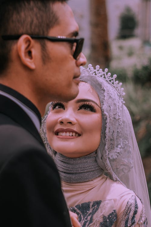 Man in Black Suit Standing Beside a Woman in Bridal Hijab Dress