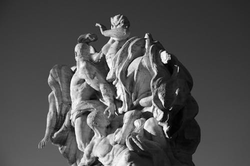 From below of black and white allegorical marble sculpture located on Ponte Vittorio Emanuele II bridge on sunny day in Rome