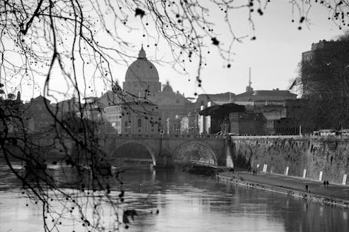 Amazing black and white scenery of ancient arched Ponte Sant Angelo bridge over calm river flowing in Rome near famous St Peters Basilica