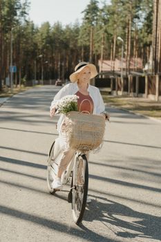 一位年长的妇女戴着遮阳帽，在户外阳光下骑着自行车