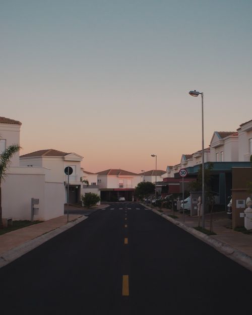 Free A peaceful suburban neighborhood street at dusk with modern houses and soft twilight sky. Stock Photo