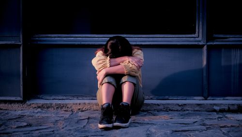 Free A solitary woman sits with her arms crossed and head down, depicting loneliness. Stock Photo