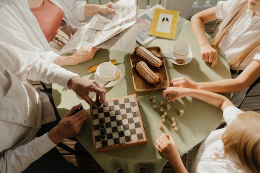 一家人在阳光明媚的桌旁享用茶点、下着国际象棋，象征着团聚