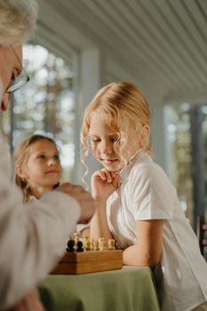 年轻女孩在室内与祖父母下棋，增进了家庭关系