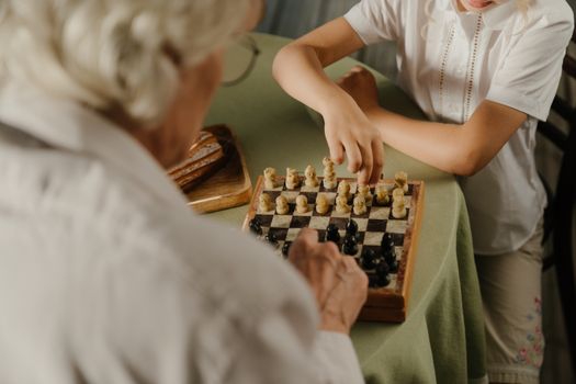 双手特写下国际象棋的镜头，突出了舒适家庭环境中的家庭纽带与战略游戏玩法
