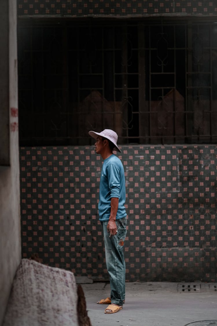 Attentive Ethnic Man In Hat Near Old Building