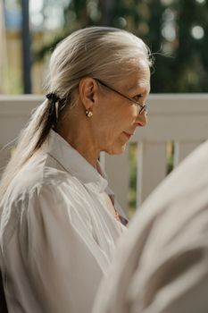 一位头发花白、戴着眼镜的资深妇女坐在宁静的户外环境中