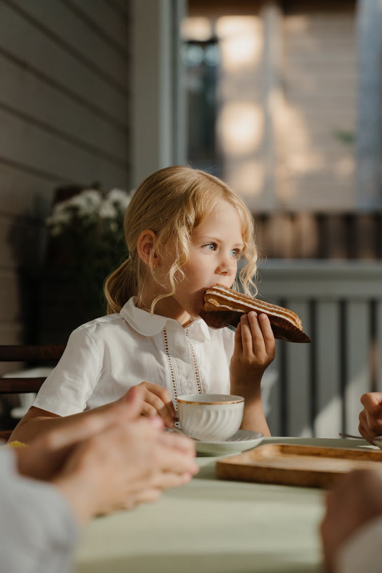 Girl Eating A Bread And Holding A Tea Cup