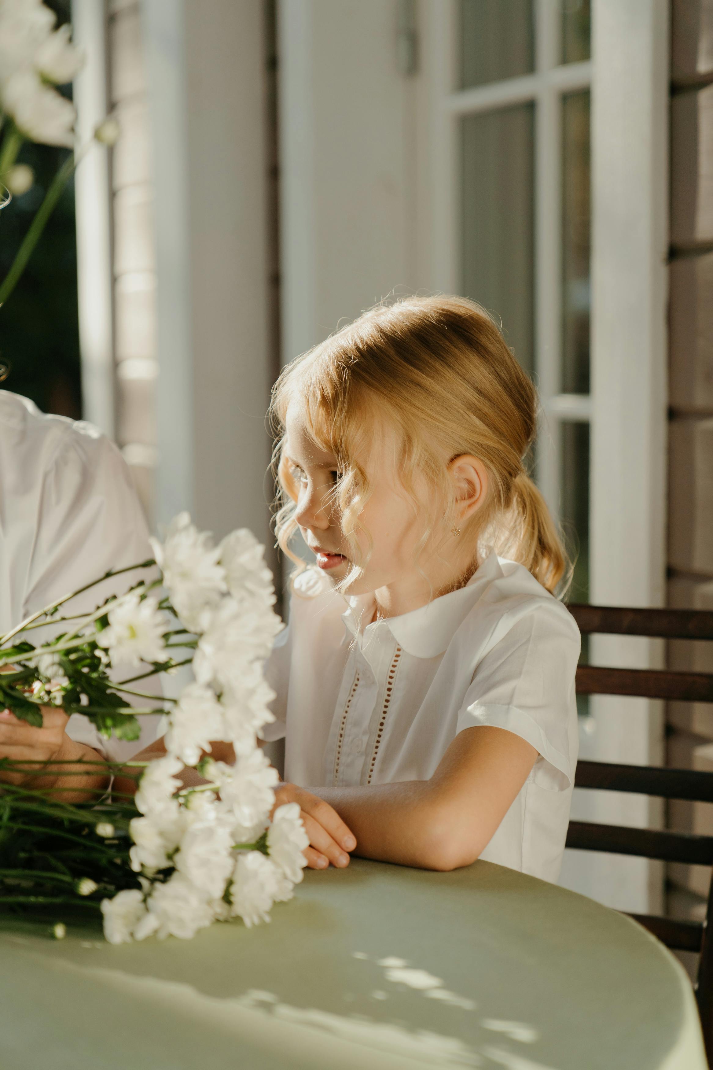 girl in white blouse beside a bunch of white flowers