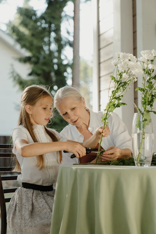 An Elderly Woman and a Girl Cutting Flowers