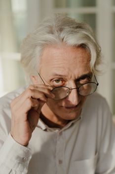 一位戴着眼镜、穿着白衬衫的高级男子正在调整镜框