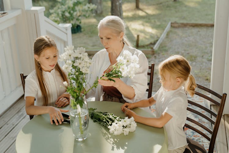 Grandma With Girls Arranging The Flowers On Vase 