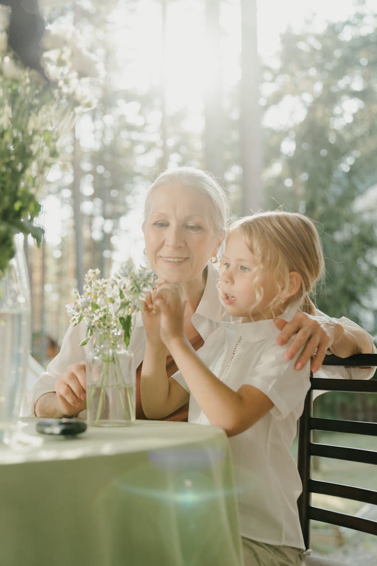 Elderly Woman And A Girl Sitting At A Table