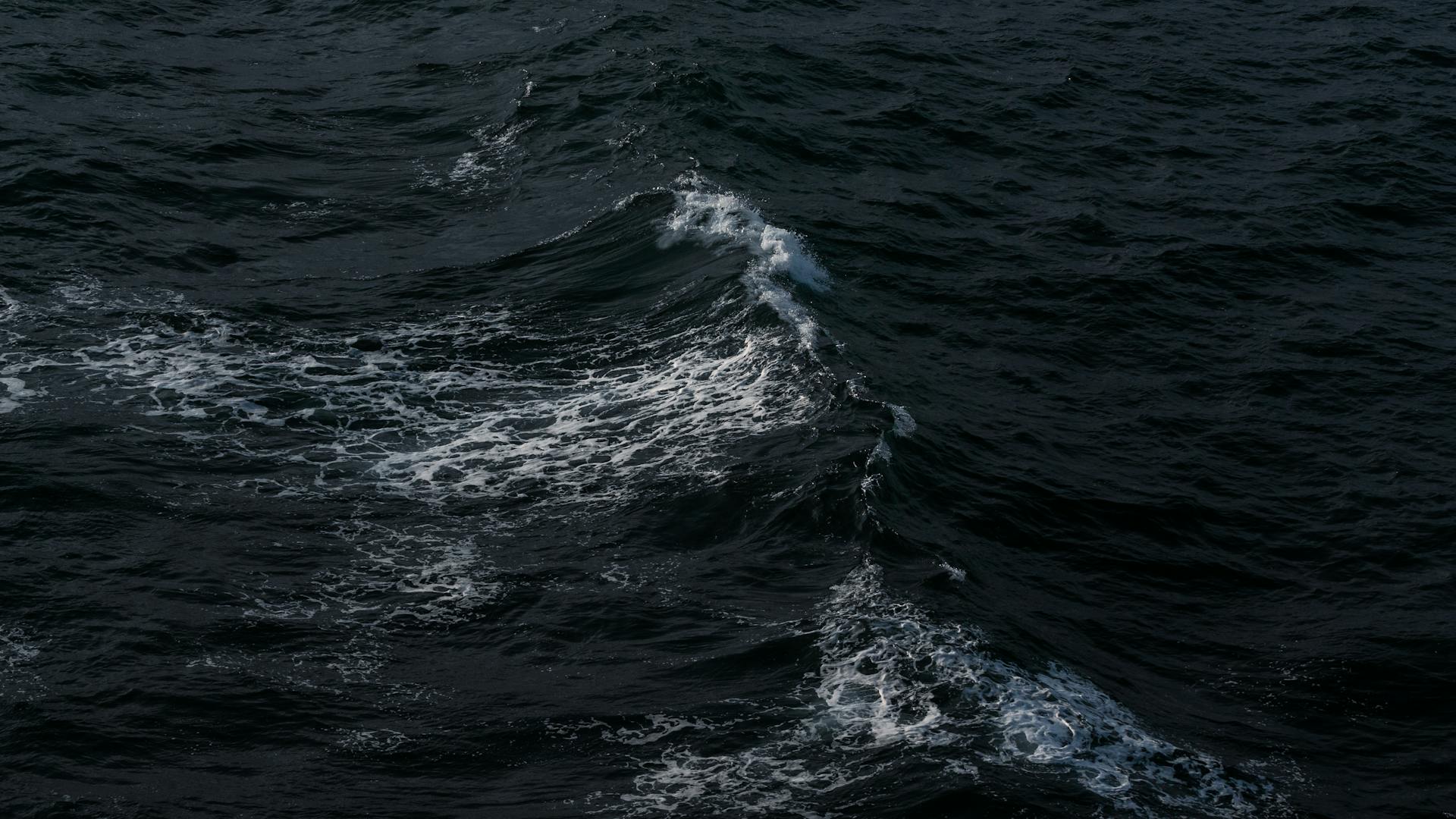 Capture of dark ocean waves with foam, reflecting a moody ambiance off the Alaskan coast.