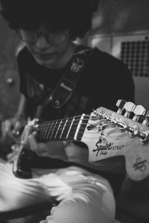 Free A black and white image of a guitarist playing indoors, focusing on the guitar. Stock Photo