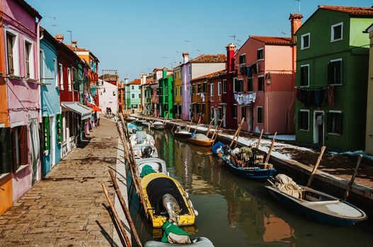 Charming canal scene in Venice with colorful houses and boats reflecting Italian architecture.