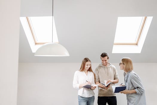 Three colleagues engaged in a productive team meeting inside a bright, modern office with skylights.