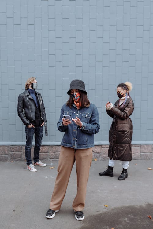 People Wearing Jackets and Pants Standing Near Tiled Wall