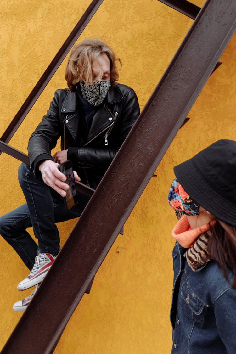 Man In Black Leather Jacket Sitting On A Metal Ladder