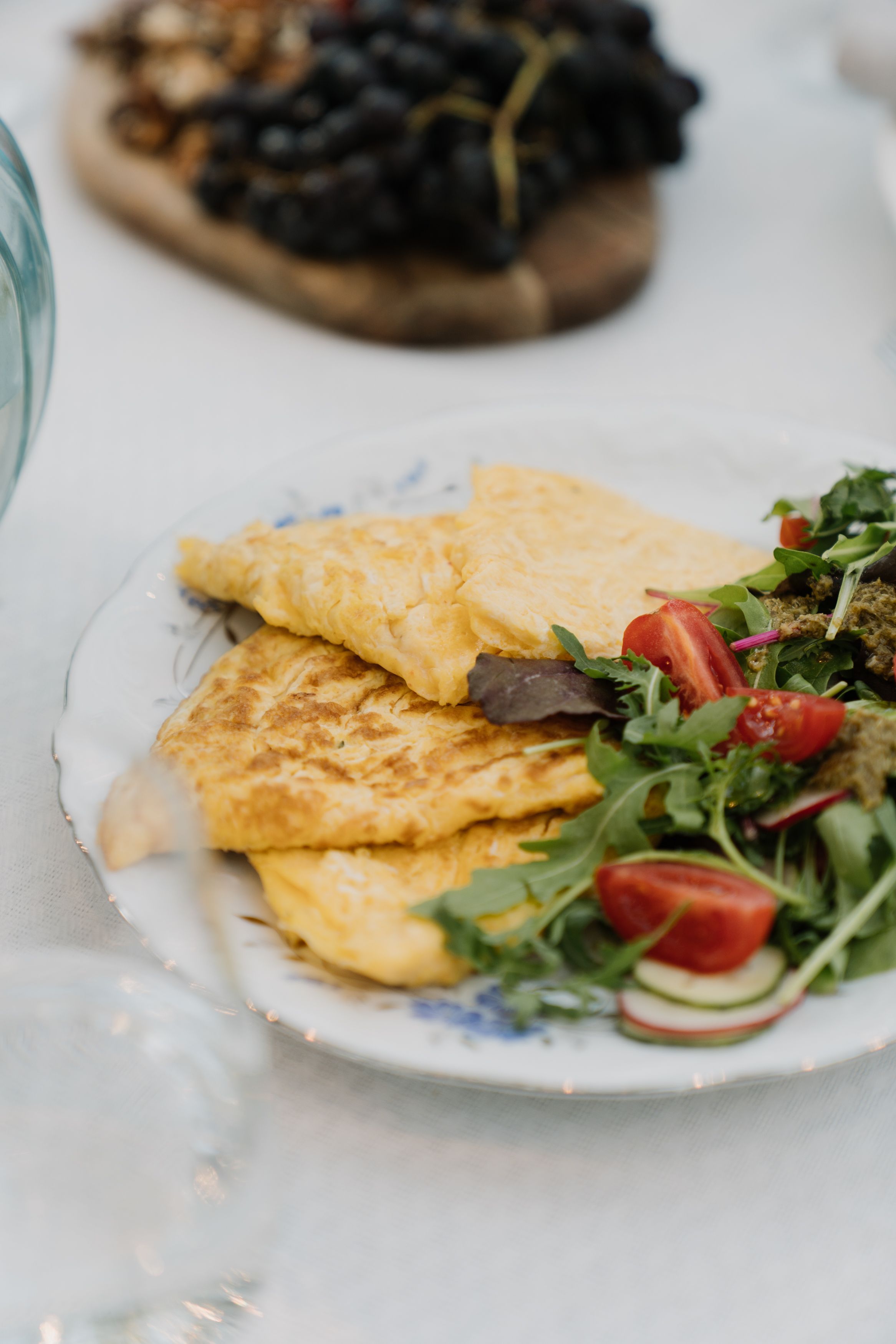 A delicious omelette served with a fresh green salad on a decorative porcelain plate.