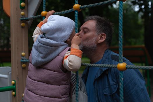 Grandfather Kissing Grandchild on Playground
