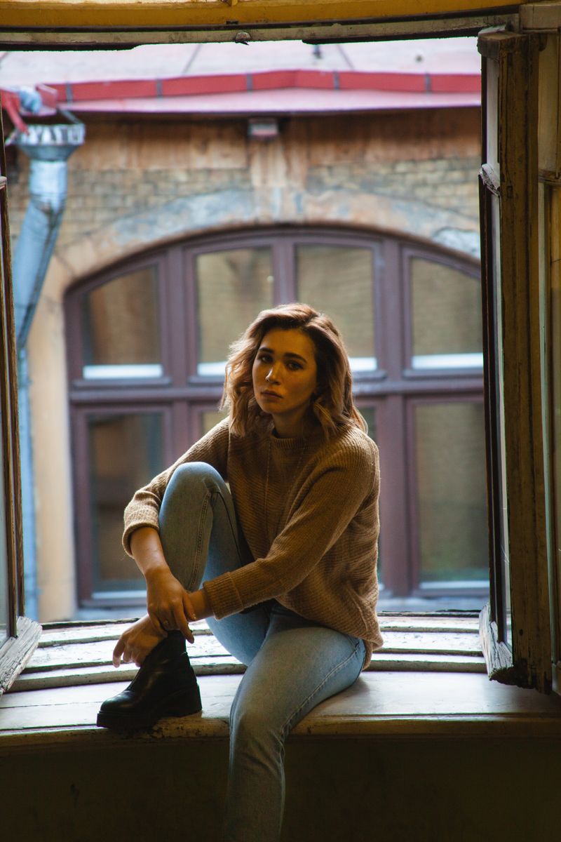 Woman sitting on a window sill gazing outside