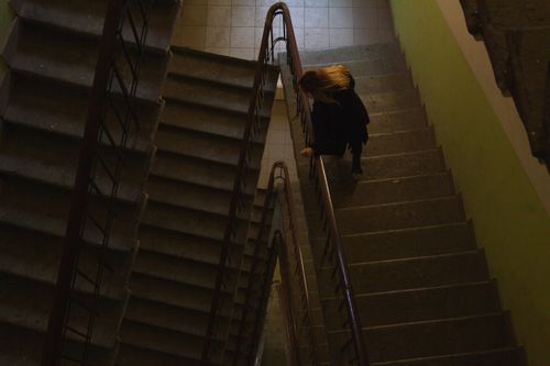 Free Top view of a woman walking down a dimly lit stairwell in a building. Stock Photo