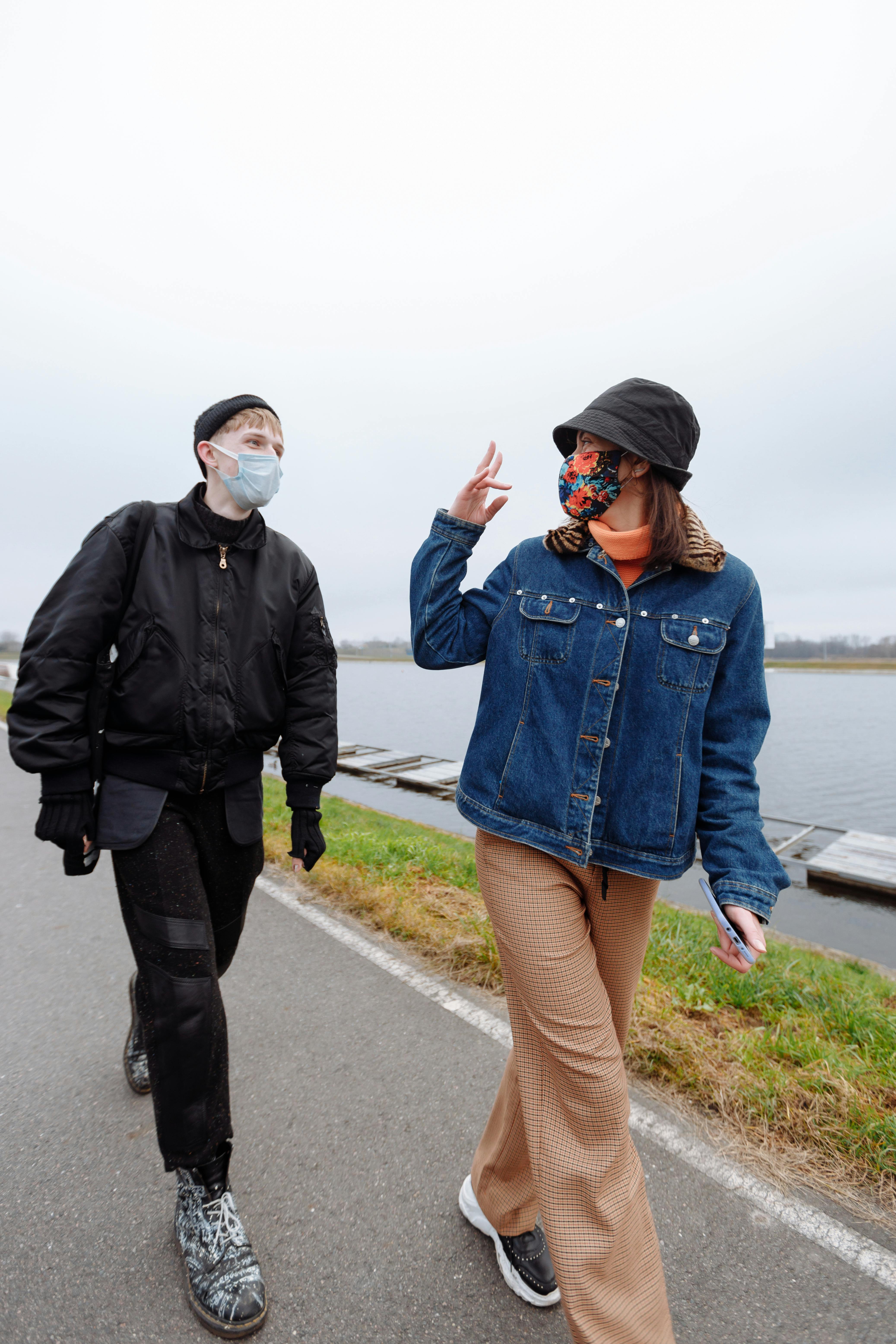 两个戴着口罩的人沿着河边的小路，在户外交谈