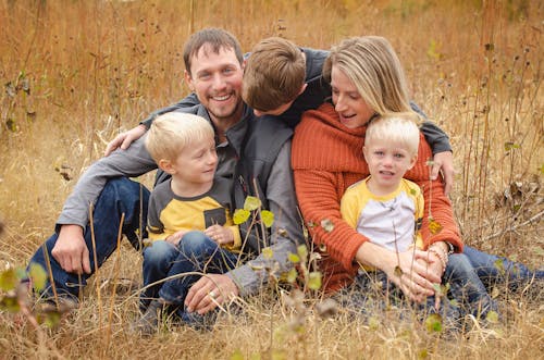 A Family Sitting on Brown Field