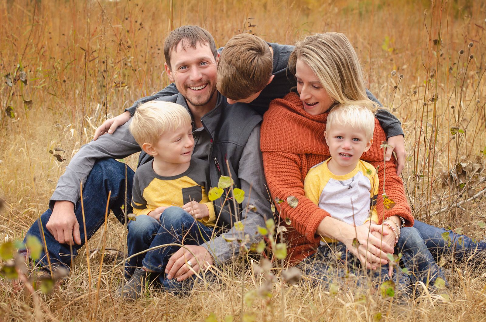 A family of five walking together through an open field in autumn light.