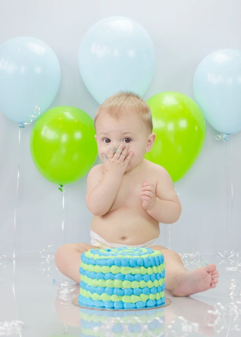 Charming baby enjoying a messy cake smash with colorful balloons