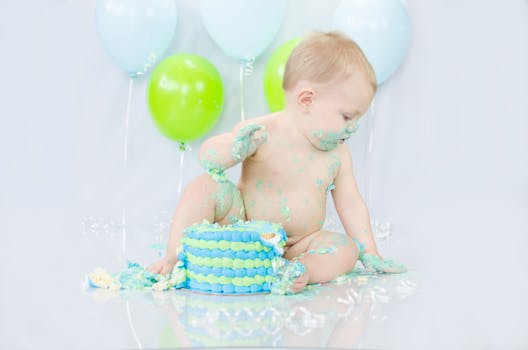 Adorable baby enjoying a messy cake smash during a colorful birthday celebration.