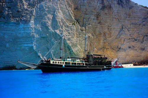 Black Ship at Sea Near Rock Formation