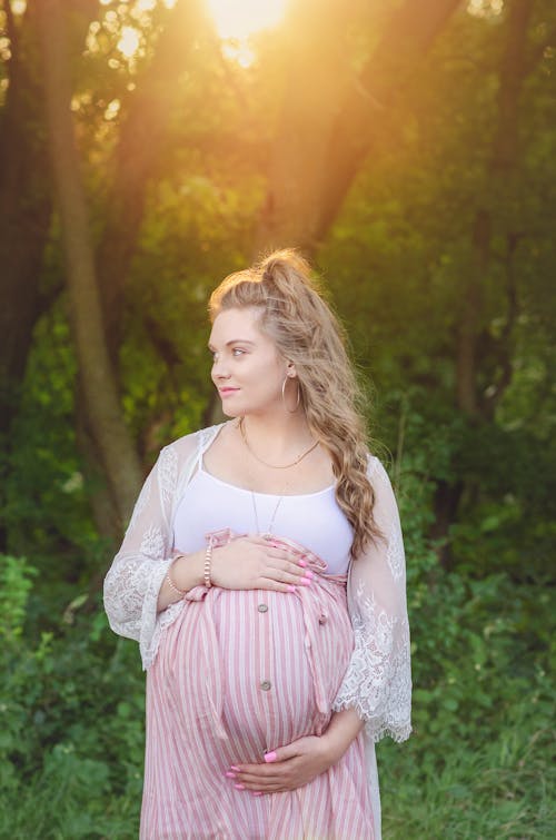 Free Selective Focus Photo of a Blonde Mother Holding Her Baby Bump while Looking Away Stock Photo